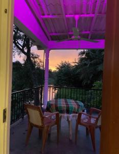 una mesa y 2 sillas en un porche con luces moradas en Home by the river, en Bollegala