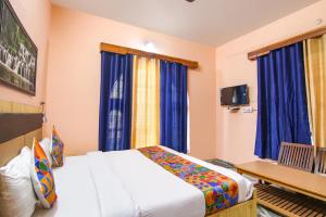 1 dormitorio con 1 cama y cortinas azules en FabExpress Malti Guest House en Kulu