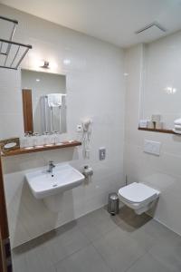 a white bathroom with a sink and a toilet at Hotel Toč in Lipova Lazne