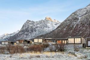 a house in the mountains with mountains in the background at Luksushytte sentralt i Lofoten in Kleppstad