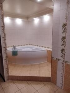 e bagno con vasca e piastrelle bianche. di SunLake Hotel Osokorki a Kiev