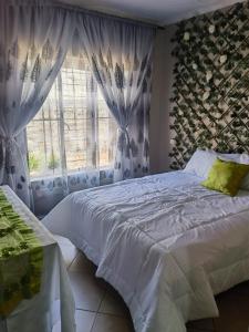 a bedroom with a white bed and a window at Mimosa's @ 44 in Roodepoort