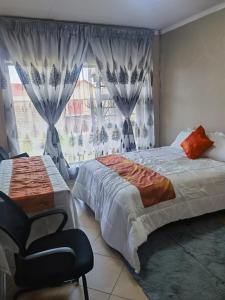a bedroom with a bed and a chair and a window at Mimosa's @ 44 in Roodepoort