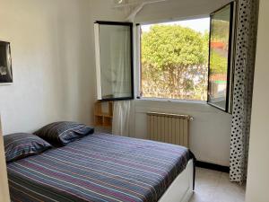 a small bedroom with a bed and a window at Maison bord de mer in Hyères