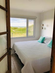 a bedroom with a large white bed and a window at La Casa de Caro Playa in Mar de Cobo