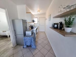 a kitchen with a refrigerator and a table in it at 24 Arniston Village, Melkbosstrand in Melkbosstrand