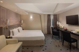 um quarto de hotel com uma cama e uma secretária em NH Paris Champs-Elysées em Paris