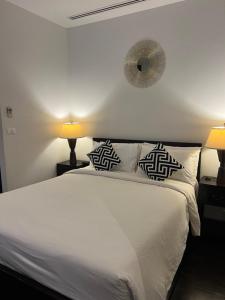 a bedroom with a white bed with two lamps and a clock at Kata Gardens Apartments in Kata Beach