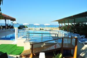 a swimming pool with chairs and the ocean in the background at Önder Yıldız Hotel in Kızılot