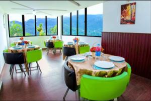 a dining room with tables and green chairs at The View Munnar in Munnar