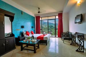 a hotel room with a bed and a table and a television at The View Munnar in Anachal