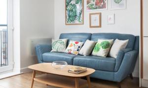 a blue couch in a living room with a table at Stunning Flat in Hull's Vibrant Fruit Market & Marina in Hull