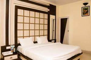 um quarto com uma cama grande e lençóis brancos em Ritumbhara Hotel & Resort em Alwar