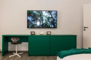 1 dormitorio con escritorio verde y TV en la pared en Old Town Premium Apartment by MRG, en Bucarest