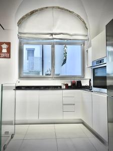 uma cozinha com armários brancos e uma janela em Da Carlin em Cesena