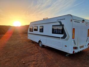 a white camper parked in the desert at sunset at Glamping Caravans In The Crater- גלמפינג קרוואנים במכתש רמון in Mitzpe Ramon