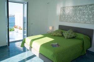 1 dormitorio con cama verde y balcón en Punta Lingua Relais - Room 2 Sunset Terrace, en Procida