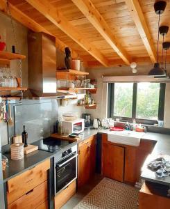 a kitchen with wooden cabinets and a large window at WAKA PICO AZORES in São Roque do Pico