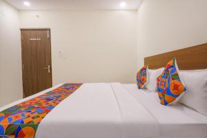 a bedroom with a large white bed with colorful pillows at FabHotel Air Live in Hyderabad