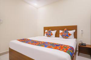 a bedroom with a large white bed with colorful pillows at FabHotel Air Live in Hyderabad