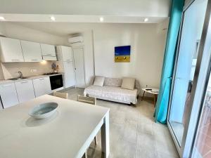 a kitchen and a living room with a couch at Angolo Mare Apartments & Rooms in Porto Pino