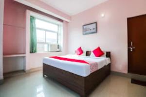 - une chambre avec un lit doté d'oreillers rouges et une fenêtre dans l'établissement Hotel Raj Shanti , Varanasi, à Varanasi