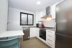a kitchen with a stainless steel refrigerator and white cabinets at Edimar 9 - Fincas Arena in Benidorm