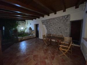 Habitación con mesa, sillas y pared de piedra. en La casa di Mene & Lù, en Pesche