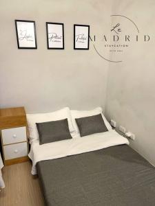 a bedroom with a bed with three pictures on the wall at Nordic-Industrial Minimalist in Manila
