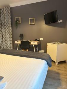 Schlafzimmer mit einem Bett, einem Schreibtisch und einem TV in der Unterkunft Dolce Vita in Mondorf-les-Bains