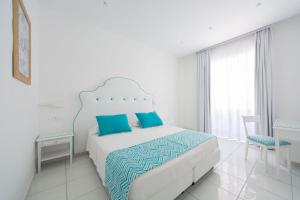 a white bedroom with a bed with blue pillows at Hotel San Francesco in Maiori