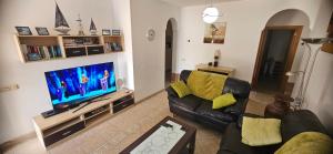 sala de estar con sofá y TV de pantalla plana en Verano Brisa Private Golf Villa, en Caleta de Fuste