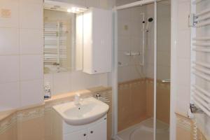 a bathroom with a sink and a glass shower at Apartament Pod Wieżyczkami in Międzyzdroje