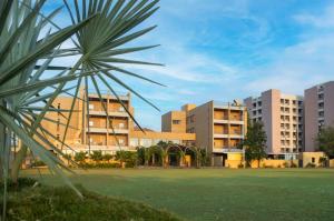 a group of buildings in a park with a palm tree at Pathikashram Nilaya in Gandhinagar