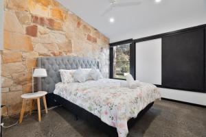 a bedroom with a bed with a stone wall at Unique and Modern Farm Stay with Pool and Foosball and Yard in Buninyong