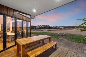a wooden bench on a deck with a view of a field at Unique and Modern Farm Stay with Pool and Foosball and Yard in Buninyong
