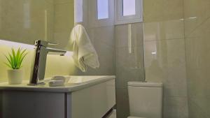 a bathroom with a sink and a toilet and a mirror at STAY Cosmo City Suites in Nicosia