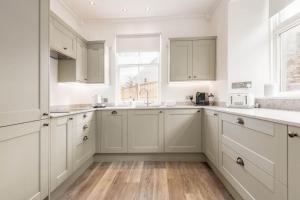 una cocina con armarios blancos y una ventana en Daisybank Kingsbarns - Beautiful 3 Bedroom Cottage en Kingsbarns