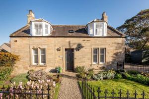 una vecchia casa in pietra con un giardino di fronte di Daisybank Kingsbarns - Beautiful 3 Bedroom Cottage a Kingsbarns