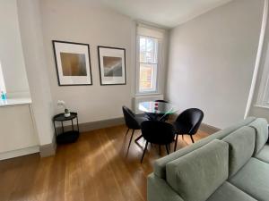 - un salon avec un canapé, une table et des chaises dans l'établissement Modern flat near Oxford Street, à Londres