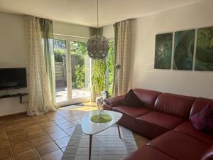 ein Wohnzimmer mit einem roten Sofa und einem Tisch in der Unterkunft Moderne Ferienwohnung mit Retro-Charme in Wülfrath