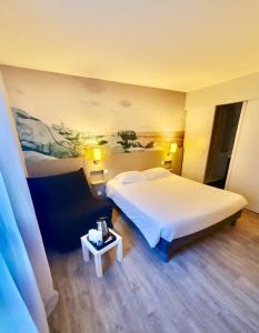 a bedroom with a large white bed and a table at Logis, Hôtel Au Chêne Vert, Saint-Brieuc Nord in Plérin