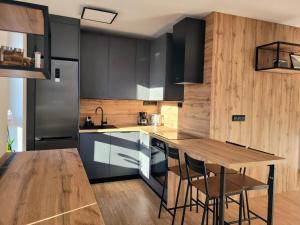 a kitchen with black cabinets and a wooden table at Apartmán Senica in Senica