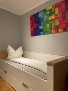 ein Bett mit einem bunten Gemälde an der Wand in der Unterkunft Quartier Scharmützelsee in Bad Saarow
