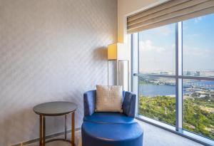 a room with a blue chair and a table and a large window at HomesGetaway-Lavish STU in Hyatt Regency Creek Heights Residences in Dubai
