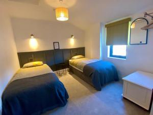 a bedroom with two beds and a table and a window at The Roadshed Apartments @ Rohans Farm in Midleton