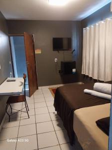 Dormitorio con cama, escritorio y TV en Pousada Portobello en Recife