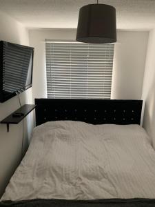 a bedroom with a bed with a black headboard and a window at 1 bed fully furnished Walsall property in Walsall