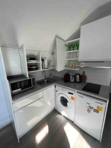 a kitchen with white cabinets and a washing machine at Amazing Location apartment in Maida Vale in London