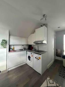 a kitchen with white cabinets and a washing machine at Amazing Location apartment in Maida Vale in London